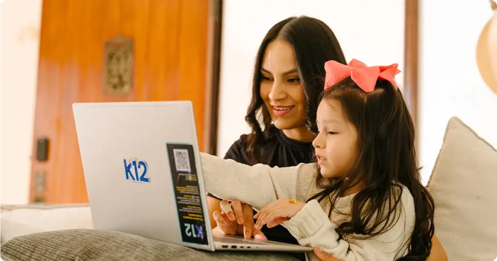 Parent and young student using a laptop together for online learning at home.